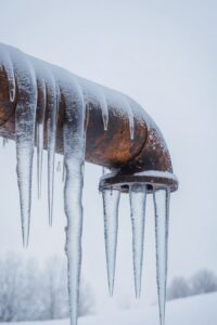 AI Generated. Icicles forming on a frozen pipe during winter in a cold climate